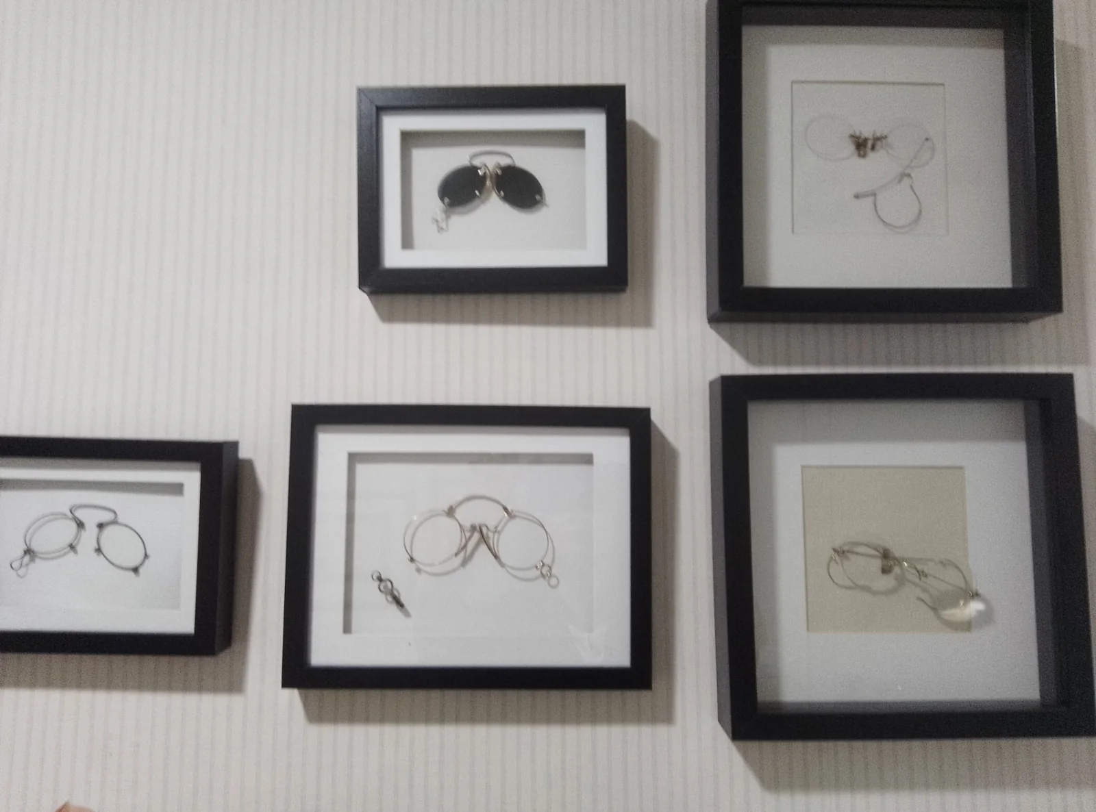 Cuadros con gafas antiguas y quevedos en la pared de la óptica